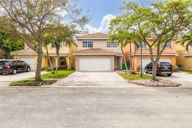 view of property featuring a garage, a tile roof, driveway, and stucco siding