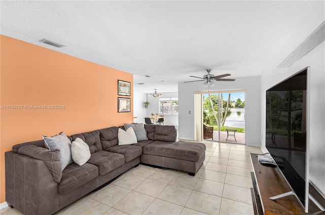 living room with light tile patterned floors, a textured ceiling, visible vents, and a ceiling fan