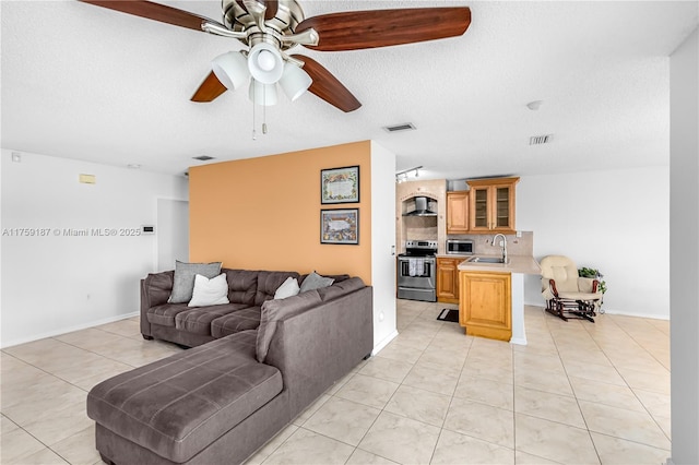 living room featuring light tile patterned floors, a textured ceiling, visible vents, and a ceiling fan