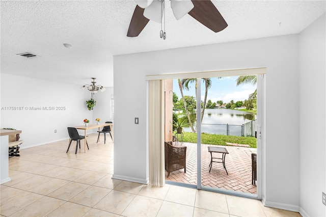 entryway with a water view, light tile patterned floors, visible vents, and a textured ceiling