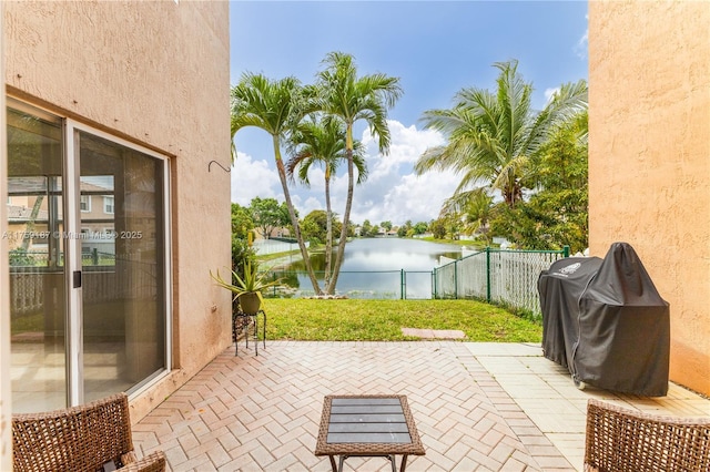 view of patio with a water view, fence, and area for grilling