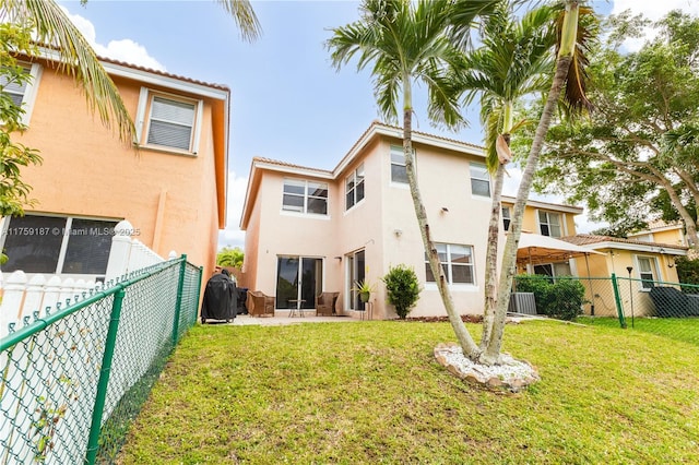 rear view of property featuring a lawn, cooling unit, a fenced backyard, and stucco siding