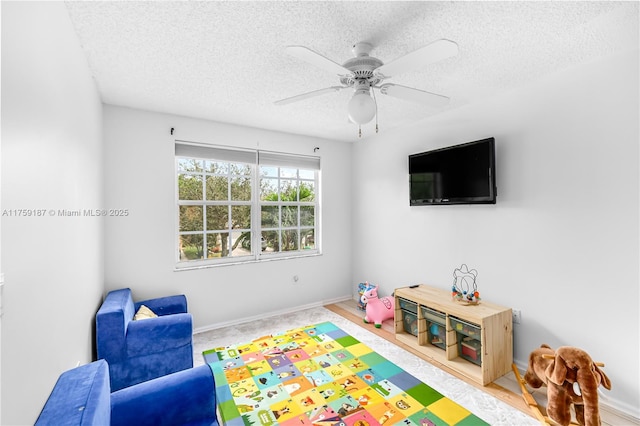 rec room featuring baseboards, a ceiling fan, and a textured ceiling