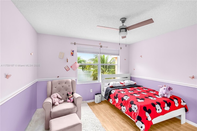 bedroom featuring ceiling fan, a textured ceiling, and wood finished floors