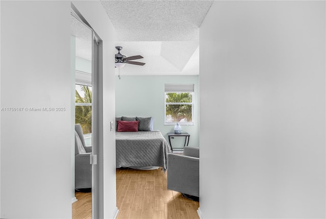 bedroom with ceiling fan, a textured ceiling, and light wood finished floors