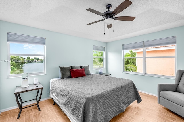 bedroom with a textured ceiling, baseboards, and wood finished floors