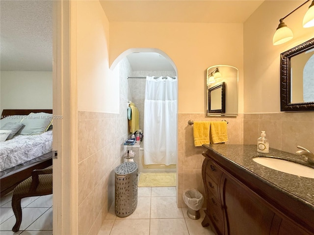 ensuite bathroom featuring tile patterned flooring, curtained shower, tile walls, ensuite bathroom, and vanity