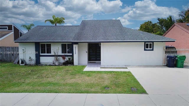 ranch-style home with a front lawn, fence, roof with shingles, and stucco siding