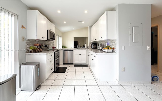 kitchen with light tile patterned floors, appliances with stainless steel finishes, a healthy amount of sunlight, and vaulted ceiling