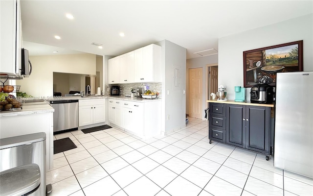 kitchen featuring tasteful backsplash, light countertops, appliances with stainless steel finishes, white cabinetry, and a sink