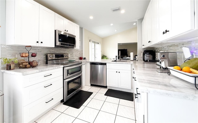 kitchen featuring light tile patterned floors, visible vents, lofted ceiling, stainless steel appliances, and white cabinetry