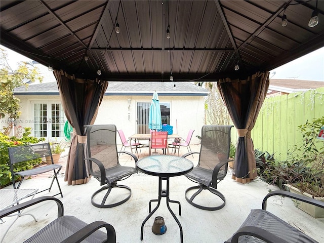 view of patio featuring a gazebo, french doors, and fence