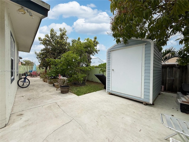 view of patio / terrace featuring a storage unit, an outbuilding, and a fenced backyard