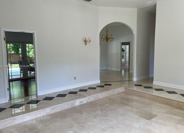 spare room with arched walkways, french doors, a towering ceiling, and baseboards