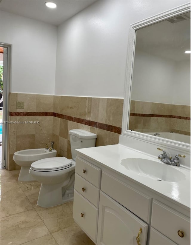 bathroom featuring toilet, recessed lighting, vanity, tile walls, and a bidet