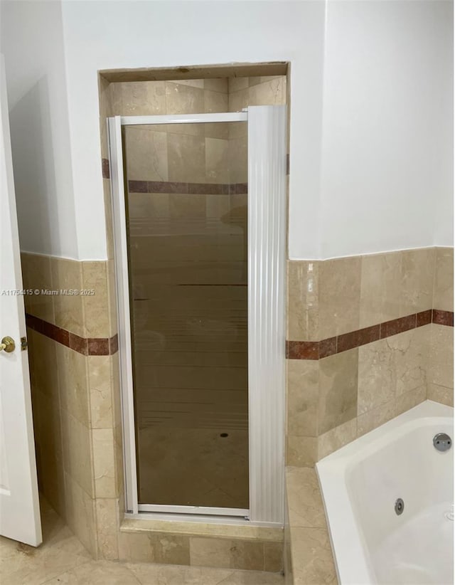 full bathroom featuring a stall shower, tile walls, and a whirlpool tub