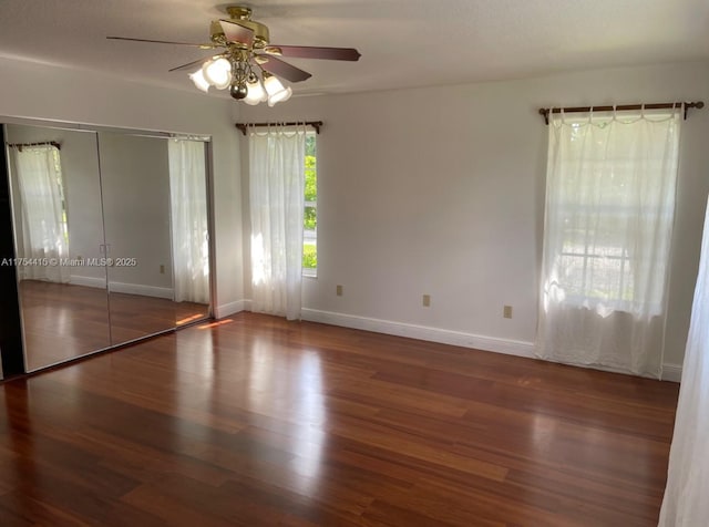 interior space with wood finished floors, a ceiling fan, and baseboards