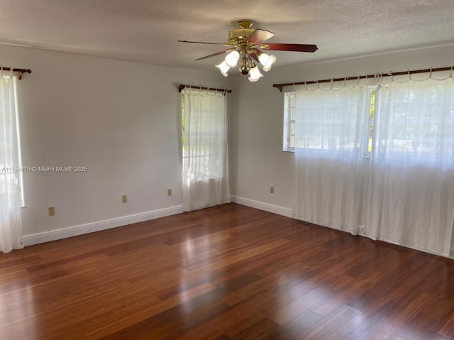 empty room with ceiling fan, a textured ceiling, baseboards, and wood finished floors