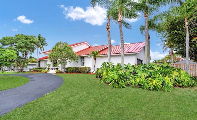 view of front of property with metal roof, fence, stucco siding, a standing seam roof, and a front yard