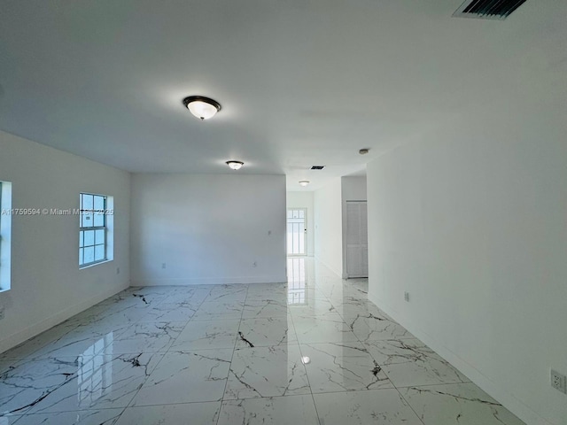 empty room with visible vents, marble finish floor, and baseboards