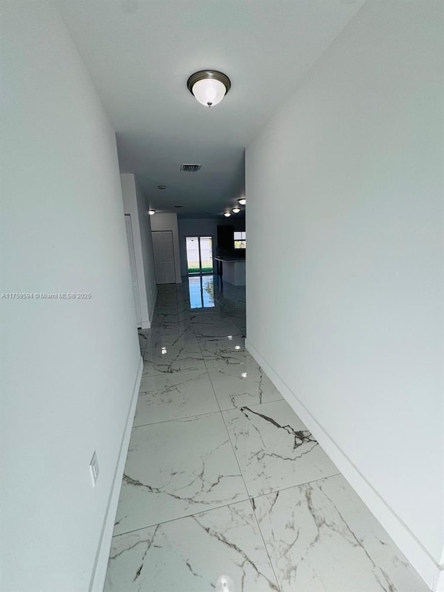 hallway featuring visible vents, marble finish floor, and baseboards