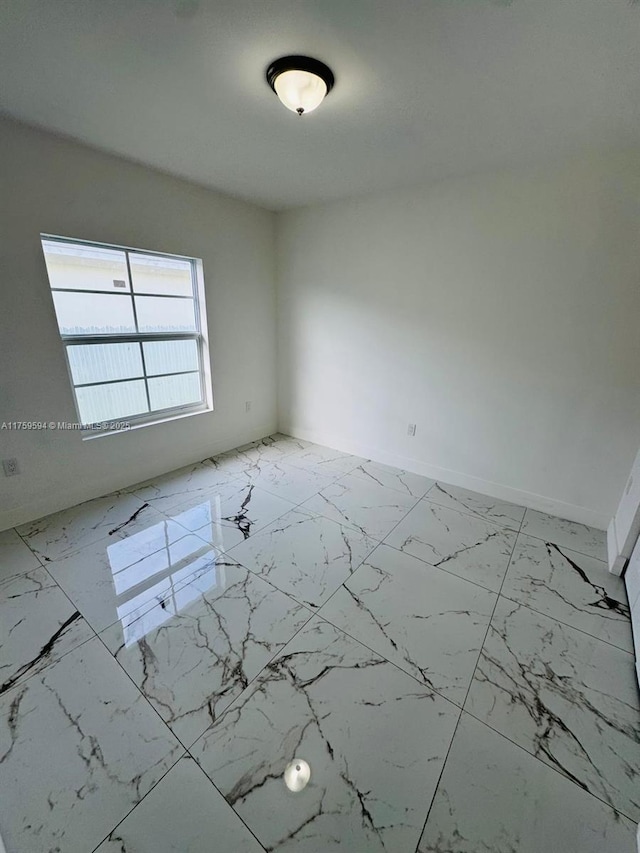 empty room with baseboards and marble finish floor