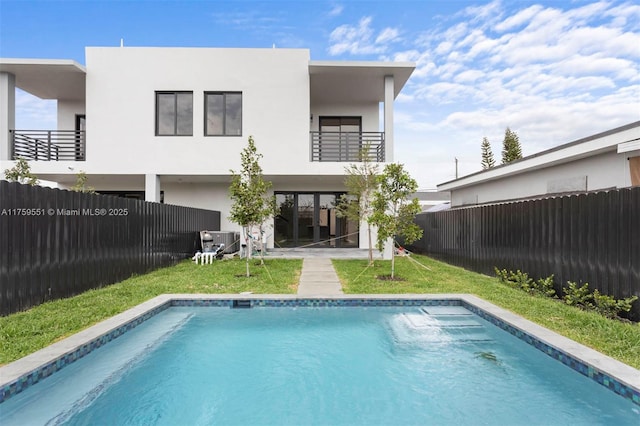 rear view of property with central AC unit, a fenced in pool, a balcony, a fenced backyard, and stucco siding