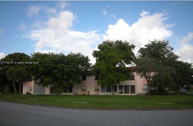 view of property hidden behind natural elements featuring a front yard