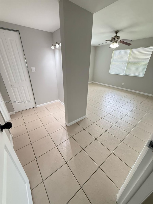 empty room featuring a ceiling fan, baseboards, and light tile patterned floors