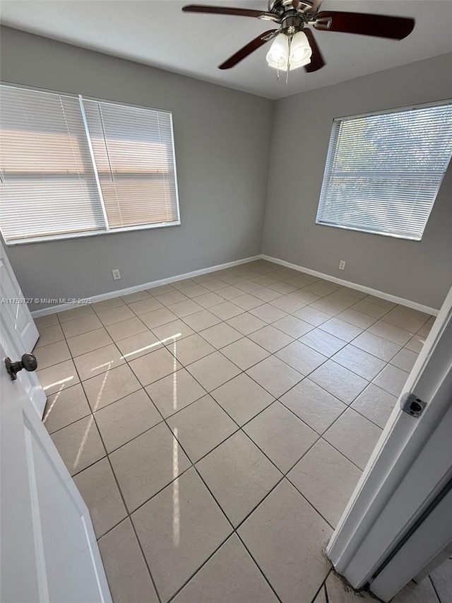 unfurnished room featuring light tile patterned floors, ceiling fan, and baseboards