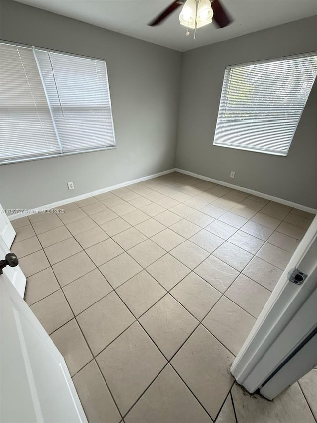 spare room with light tile patterned floors, ceiling fan, and baseboards