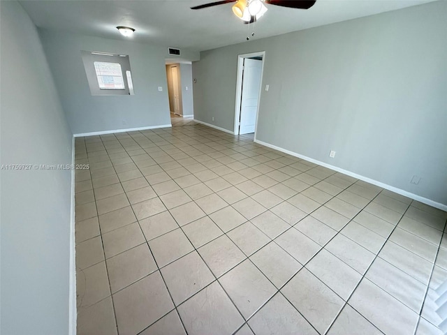 empty room featuring ceiling fan, visible vents, and baseboards