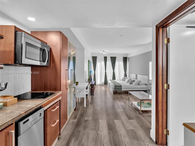 kitchen featuring appliances with stainless steel finishes, recessed lighting, wood finished floors, and brown cabinets