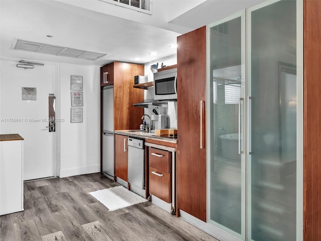 kitchen with visible vents, dark wood-style flooring, stainless steel appliances, open shelves, and a sink