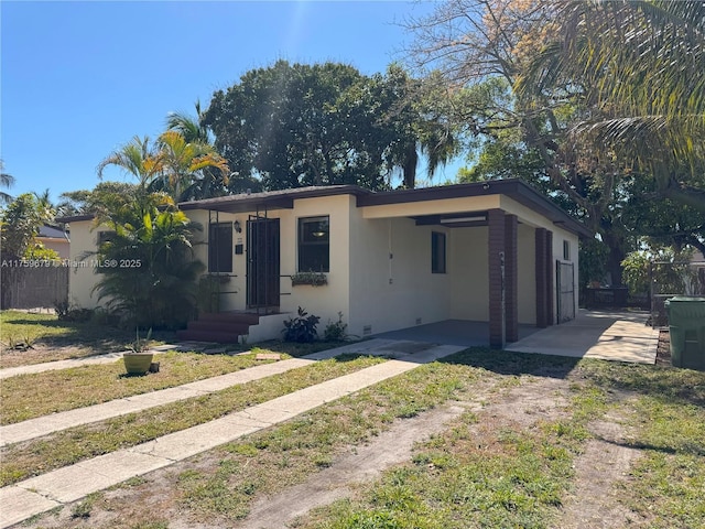 view of front of property featuring driveway, fence, an attached carport, and stucco siding