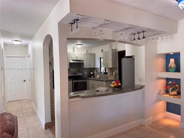 kitchen with light tile patterned floors, decorative backsplash, appliances with stainless steel finishes, a sink, and under cabinet range hood