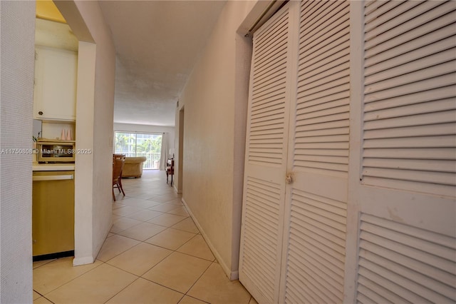 corridor featuring light tile patterned flooring and baseboards