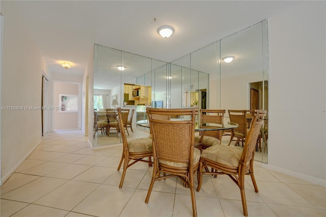 dining space featuring light tile patterned flooring and baseboards