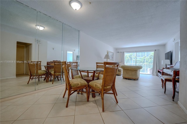 dining area featuring visible vents, a textured ceiling, and light tile patterned flooring