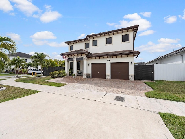 view of front of home featuring decorative driveway, an attached garage, a gate, fence, and stone siding