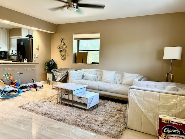 living area featuring marble finish floor, ceiling fan, and baseboards