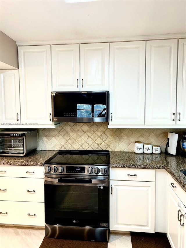 kitchen featuring black microwave, a toaster, white cabinets, tasteful backsplash, and stainless steel range with electric stovetop