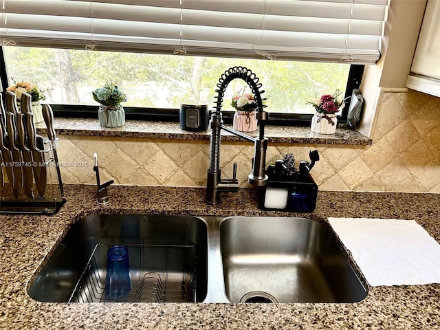 room details featuring backsplash, dark stone countertops, and a sink