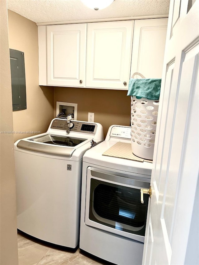 washroom with a textured ceiling, light wood-style flooring, independent washer and dryer, cabinet space, and electric panel