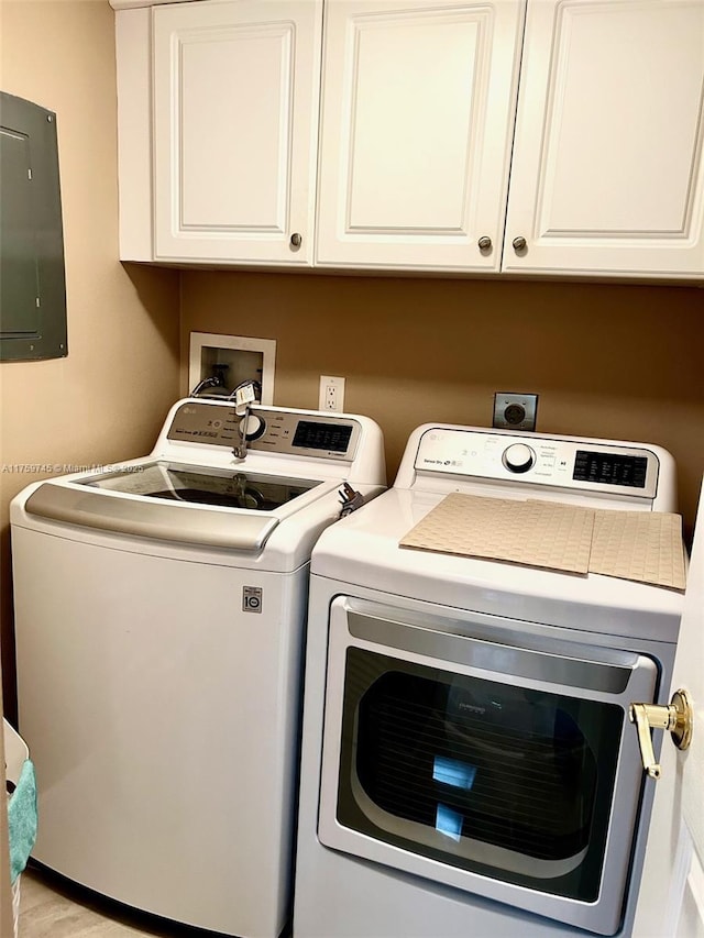 washroom featuring washer and clothes dryer, cabinet space, and electric panel