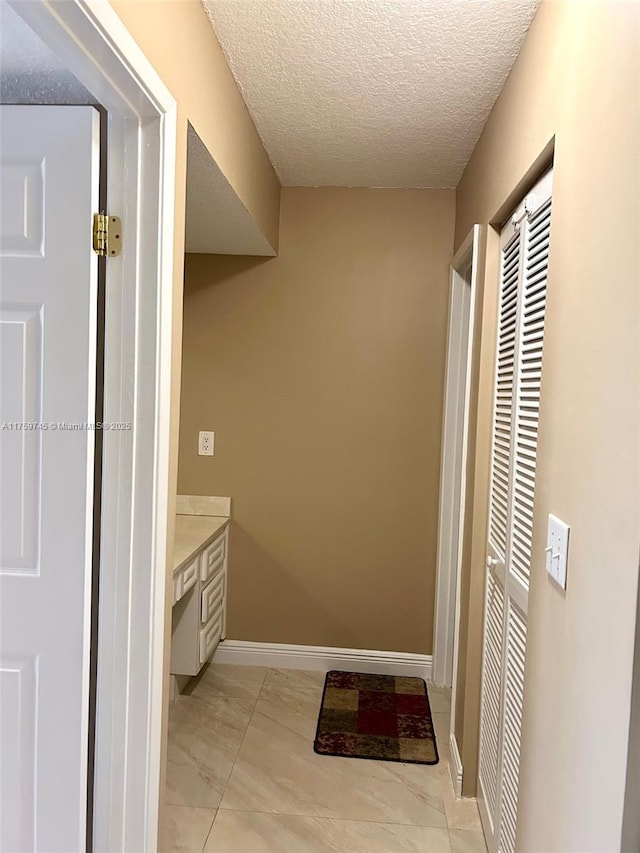 bathroom with baseboards, a textured ceiling, and vanity