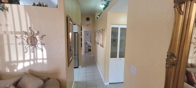 corridor with a textured wall and light tile patterned floors