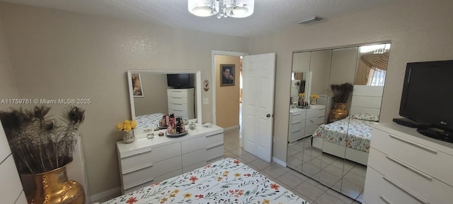 bedroom with a chandelier, light tile patterned flooring, visible vents, baseboards, and a closet