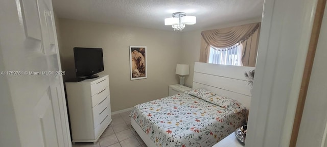 bedroom with a textured ceiling, light tile patterned floors, a chandelier, and baseboards