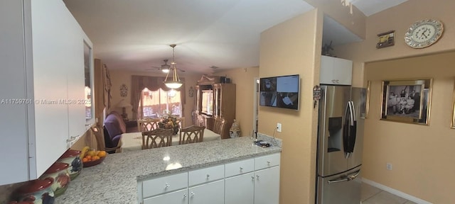 kitchen with light tile patterned floors, a ceiling fan, white cabinets, light stone countertops, and stainless steel fridge